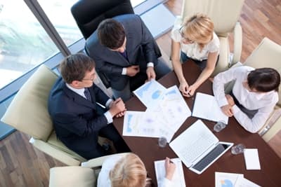 Photo d'une équipe analysant des graphiques financiers autour d'une table de réunion