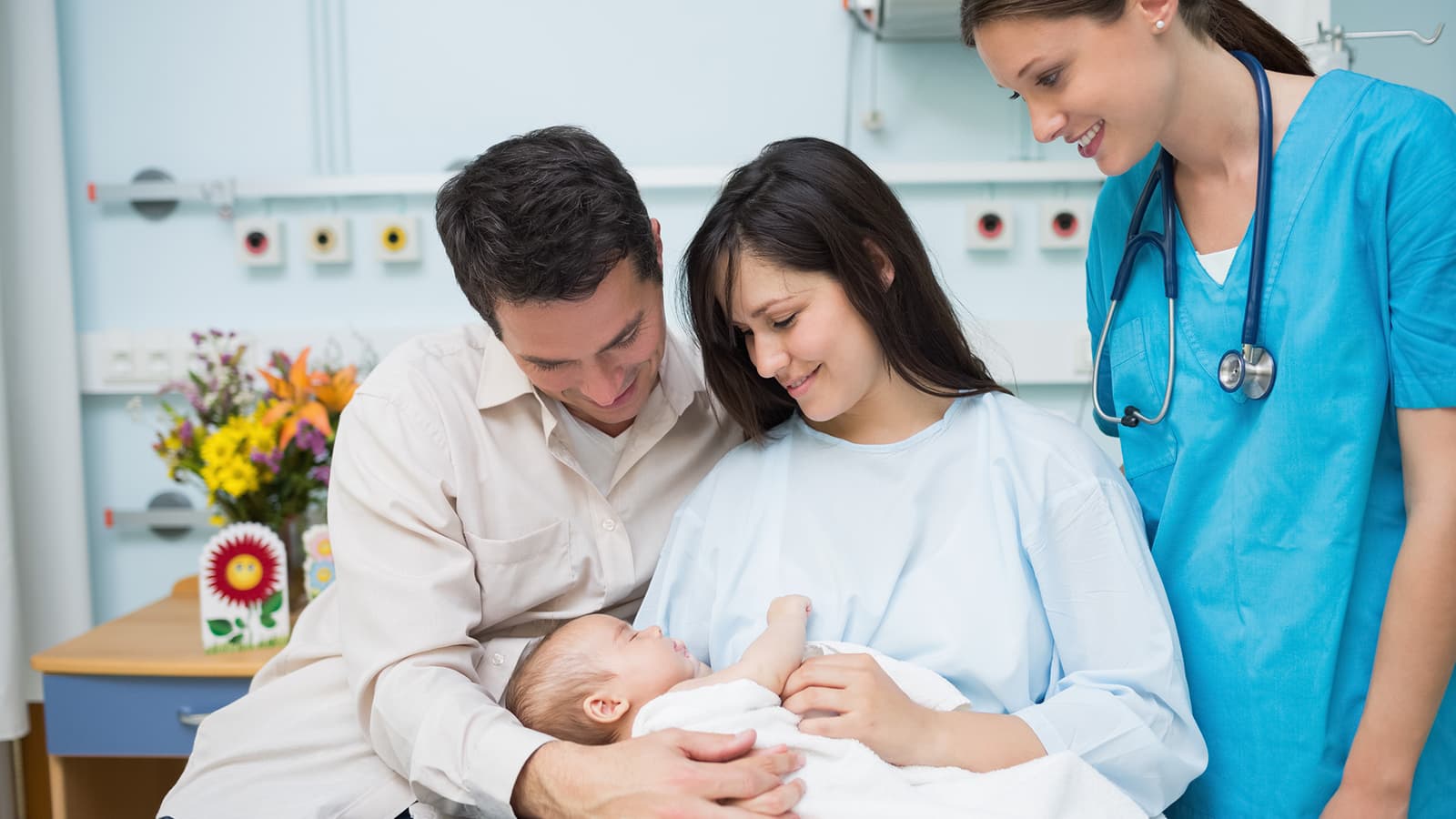 Photo d'une sage-femme en blouse bleue accompagnant de jeunes parents et leur nouveau-né en maternité