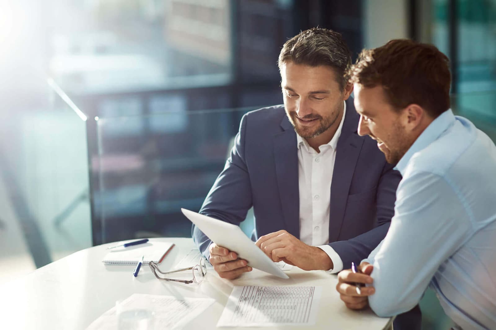 Photo de deux professionnels en costume analysant des chiffres sur une tablette au bureau