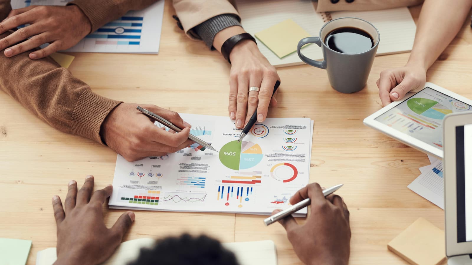 Équipe analysant des graphiques et indicateurs de performance autour d'une table lors d'une réunion produit