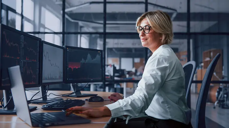 Photo d'une analyste quantitative devant des écrans affichant des courbes financières