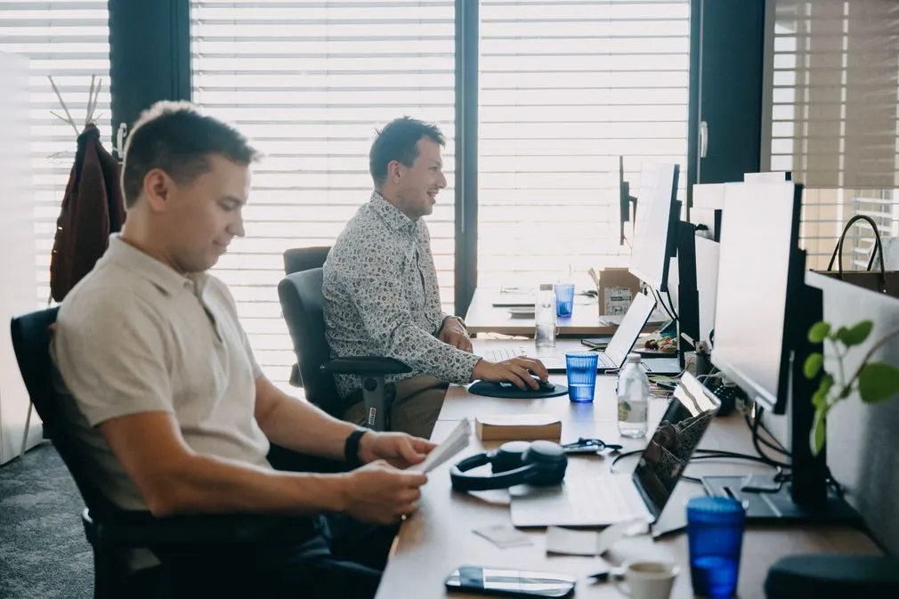 Photo de deux collaborateurs travaillant côte à côte sur leurs ordinateurs au bureau