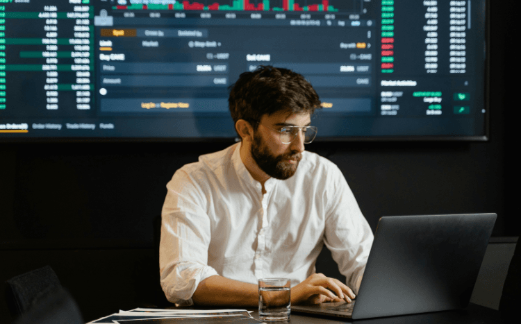 Photo d'un analyste travaillant sur son ordinateur portable devant un tableau de bord