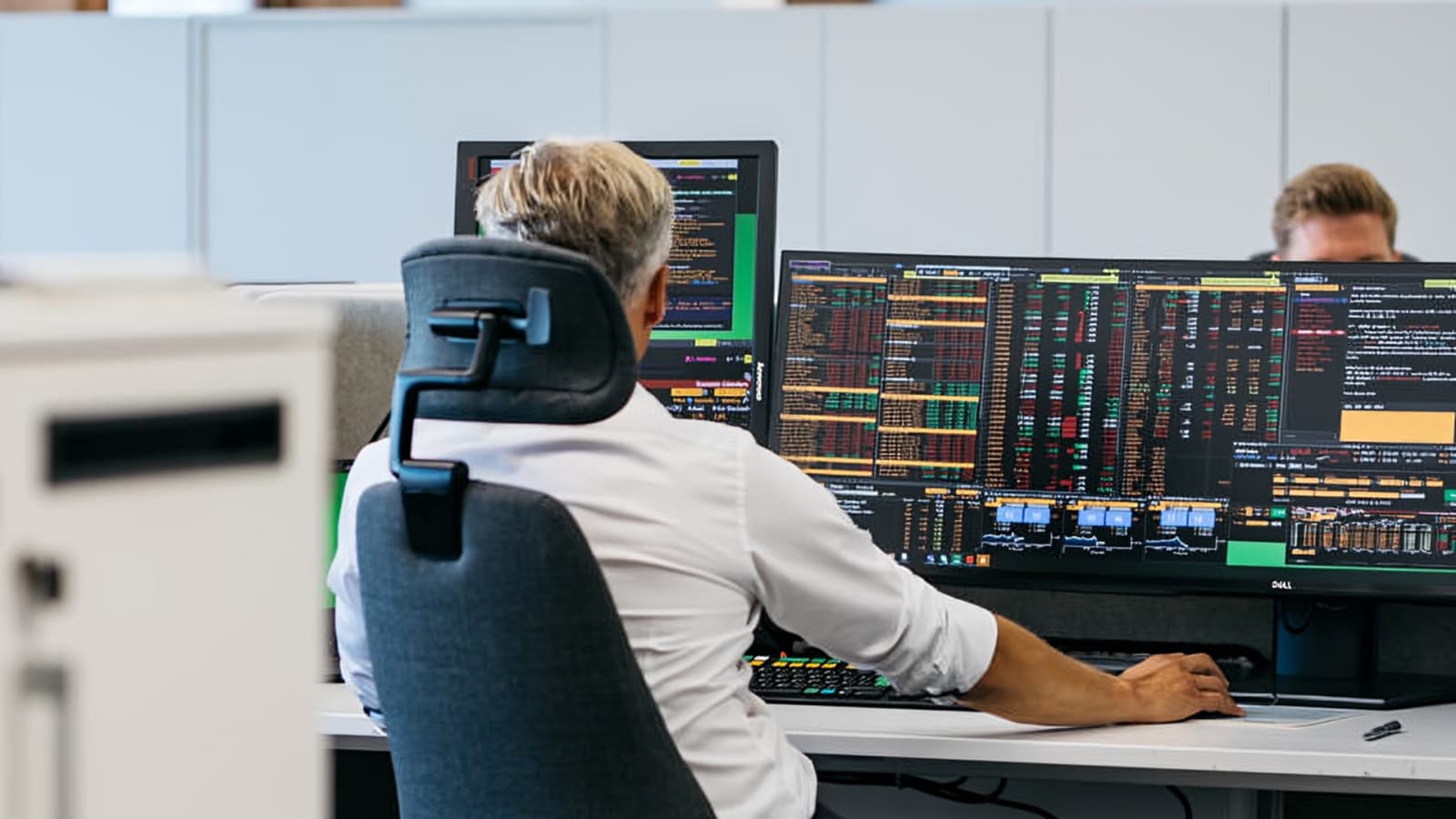 Photo d'un homme analysant des données financières sur plusieurs écrans de trading