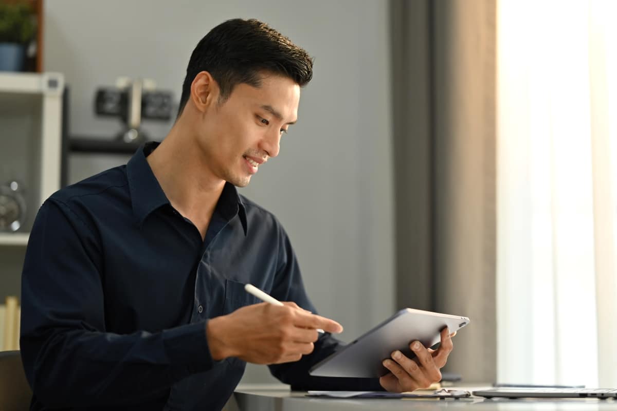 Photo d'un professionnel souriant utilisant un stylet sur une tablette à son bureau