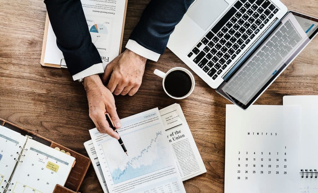 Photo d'un professionnel analysant des graphiques et documents sur un bureau en bois