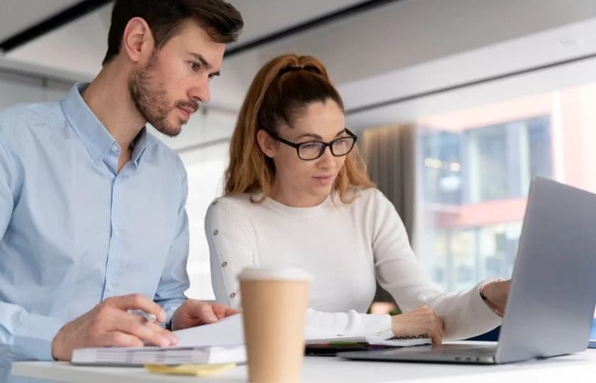 Photo de deux collègues concentrés travaillant ensemble sur un ordinateur portable au bureau