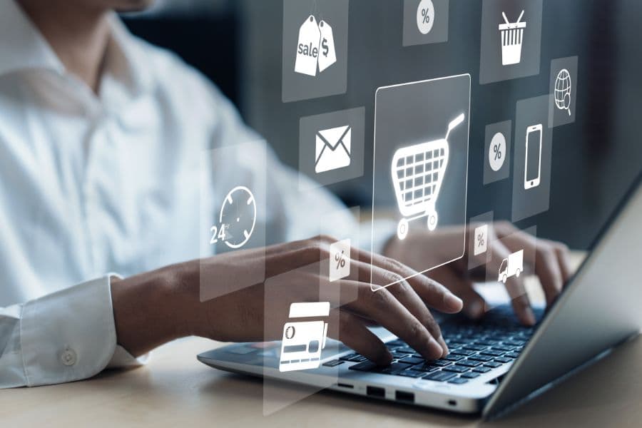 Photo de mains tapant sur un ordinateur avec des icônes de marketing digital en surimpression