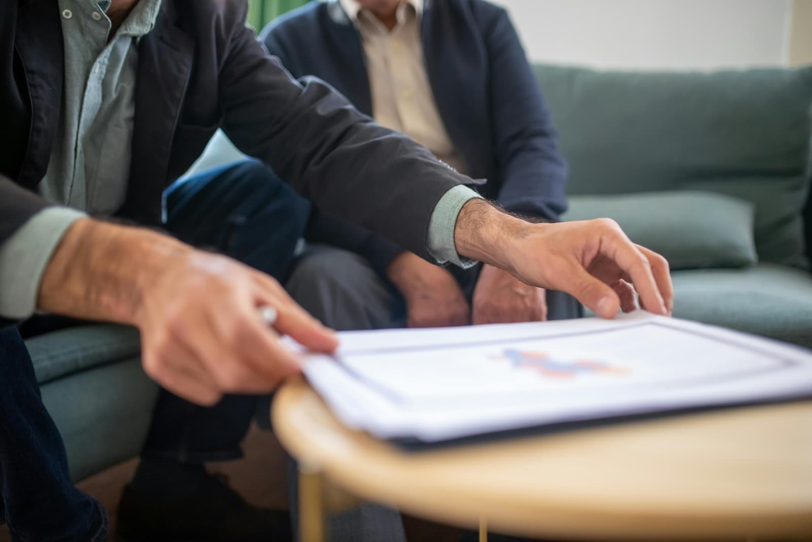 Photo de deux professionnels analysant un document avec des graphiques sur une table basse