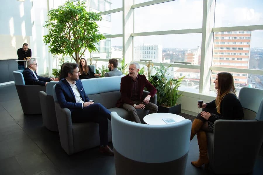 Photo de professionnels échangeant dans un espace détente lumineux avec vue panoramique sur la ville