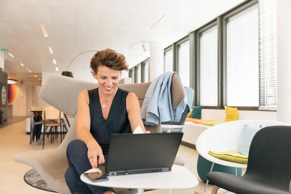 Photo d'une femme souriante travaillant sur un ordinateur portable dans un espace de coworking moderne