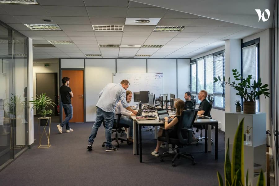 Photo d'une équipe de développeurs collaborant autour d'écrans dans un bureau lumineux