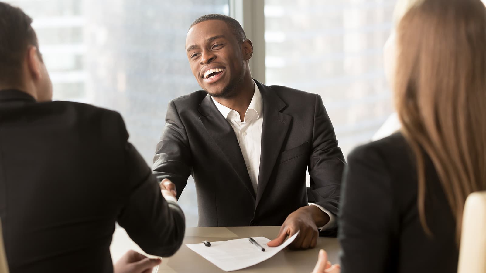 Photo d'un homme souriant en costume serrant la main d'un client lors d'un rendez-vous commercial