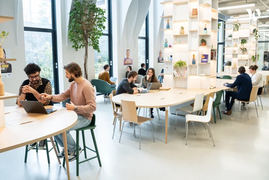 Photo d'un espace de coworking lumineux avec plusieurs personnes travaillant sur ordinateurs portables
