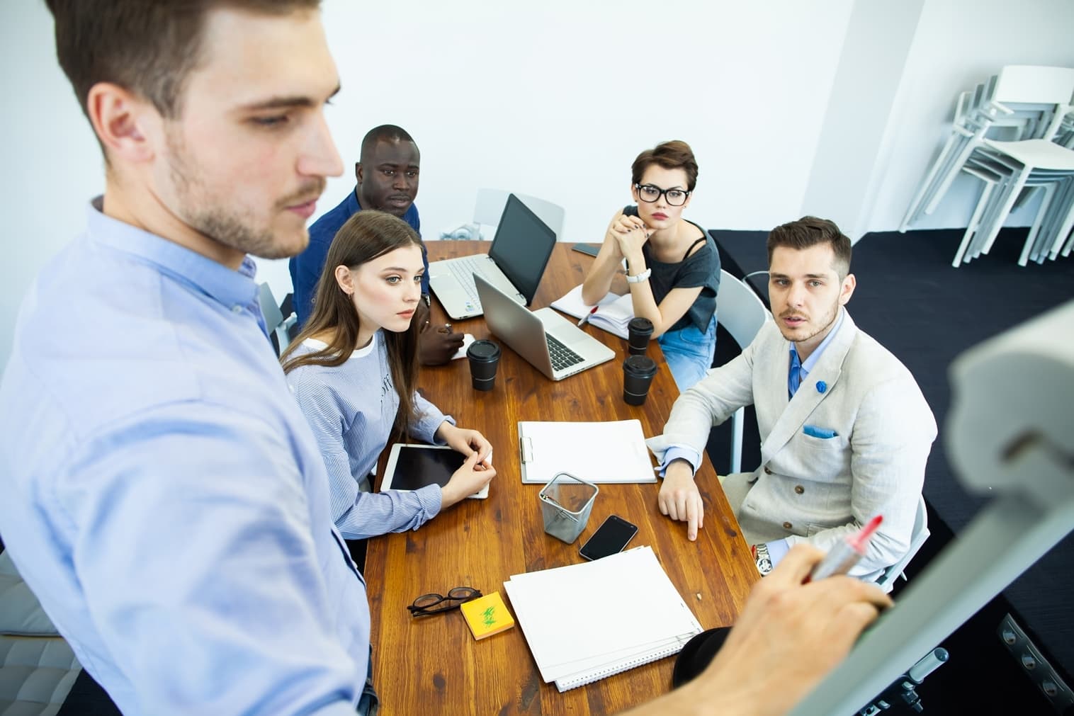 Photo d'une équipe commerciale attentive autour d'une table avec ordinateurs et tablettes en réunion
