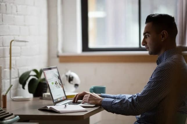 Photo d'un homme en chemise à carreaux travaillant sur un ordinateur portable dans un bureau épuré