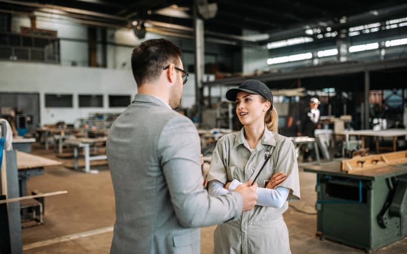 Photo d'une consultante en combinaison échangeant avec un manager dans une usine