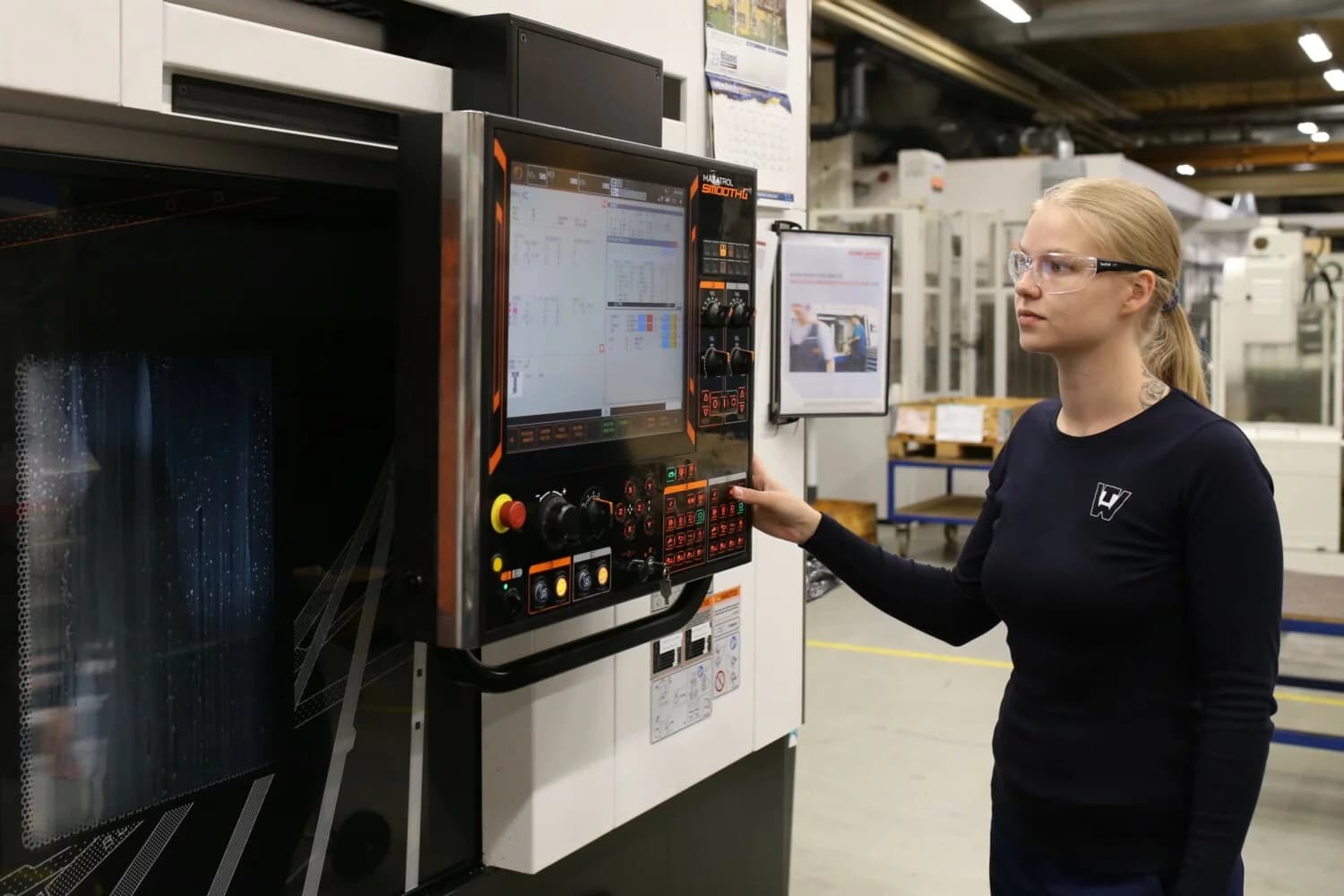 Photo d'une technicienne programmant un panneau de commande de machine industrielle