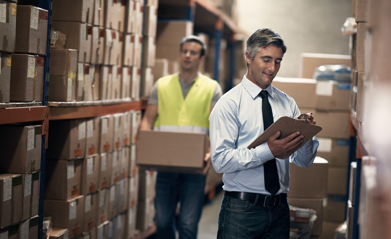 Photo d'un responsable en chemise et cravate vérifiant un inventaire dans un entrepôt de stockage