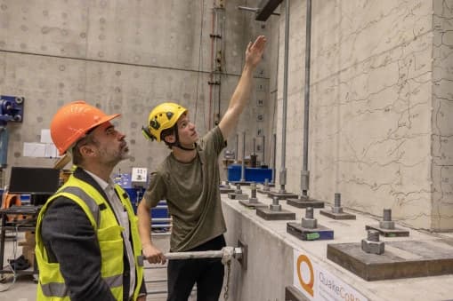 Photo de deux ingénieurs casqués analysant une structure en béton dans un laboratoire d'essais