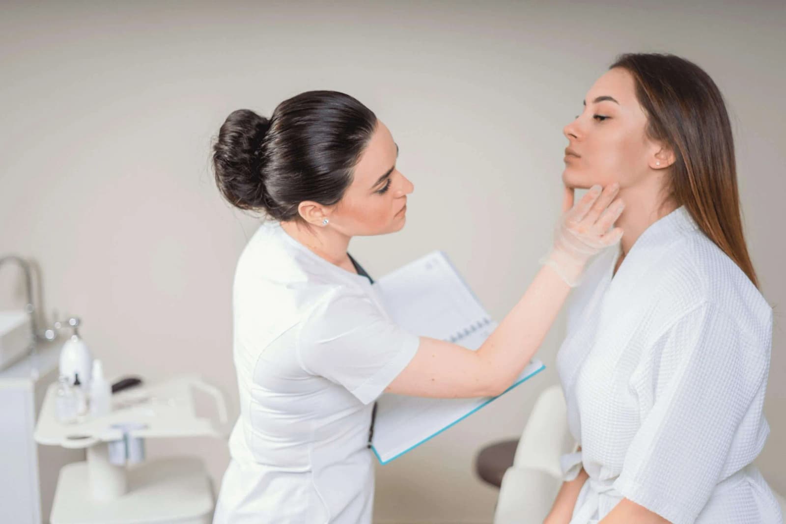 Photo d’une dermatologue examinant la peau du visage d’une patiente dans un cabinet médical