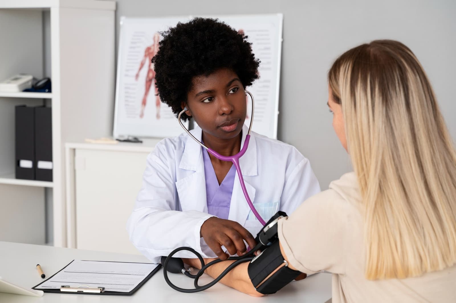Photo d'une médecin généraliste prenant la tension artérielle d'une patiente en consultation