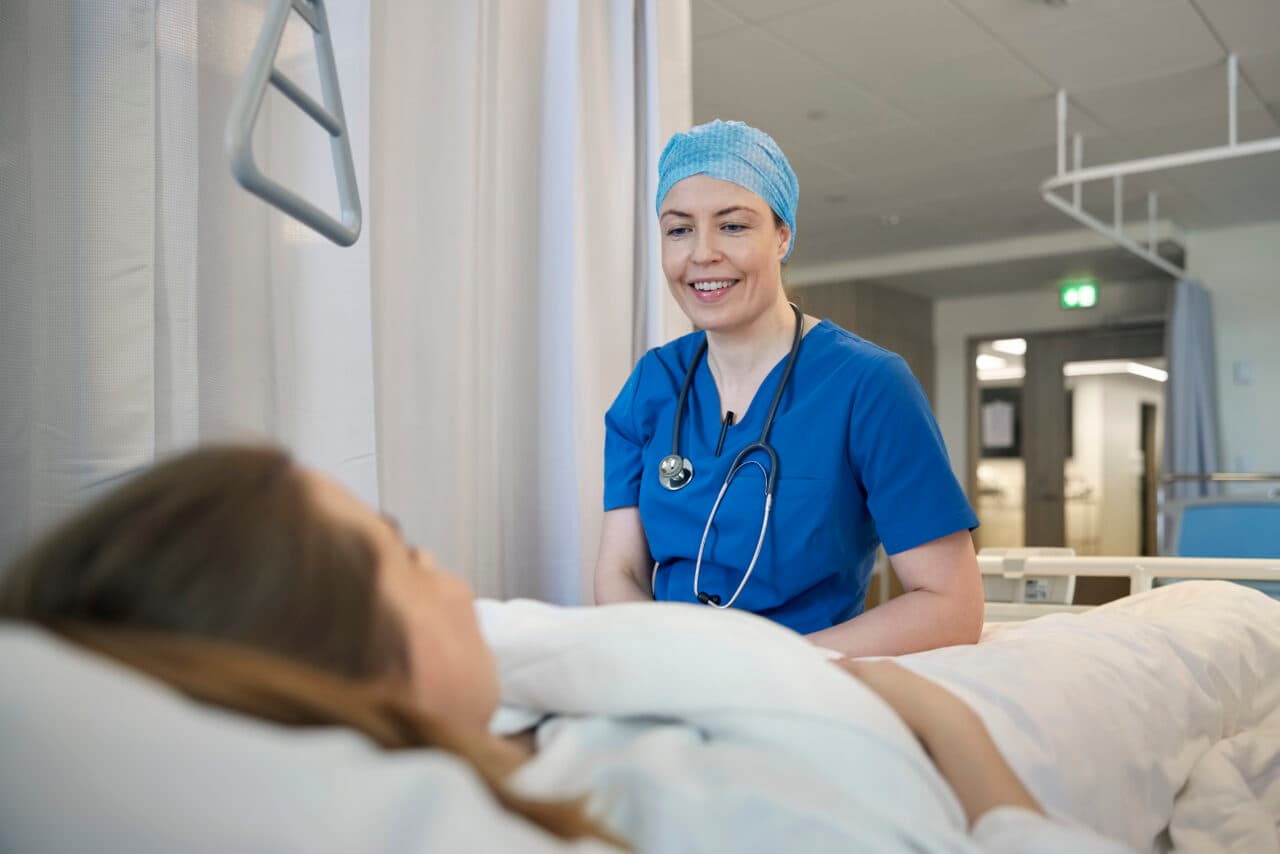 Photo d'une médecin urgentiste en tenue bleue au chevet d'une patiente hospitalisée