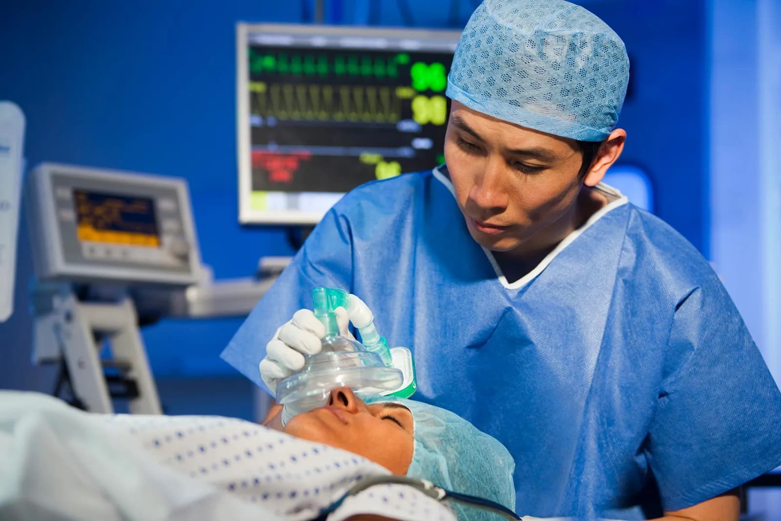 Photo d'un anesthésiste posant un masque respiratoire sur un patient en salle d'opération