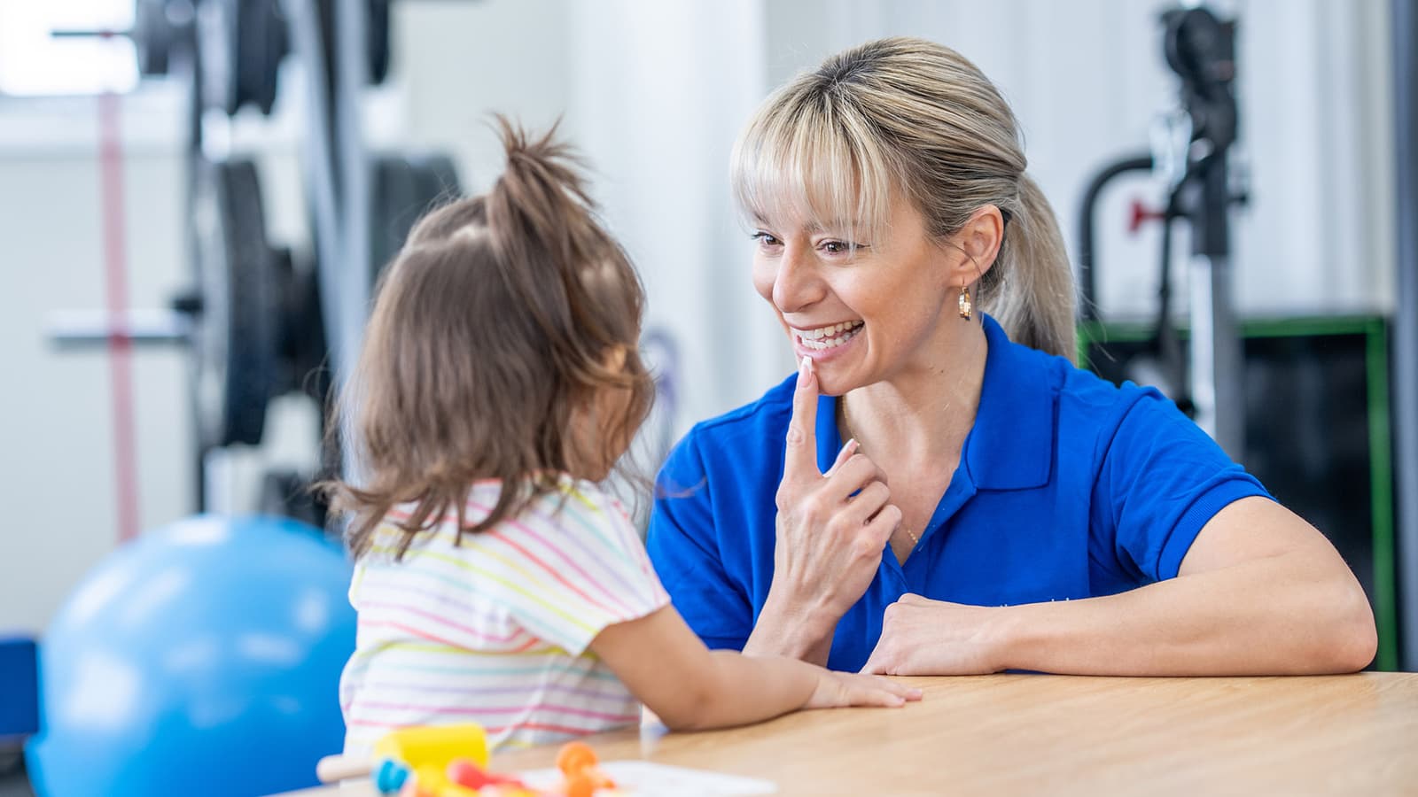 Orthophoniste travaillant avec une enfant sur des exercices de prononciation en cabinet de rééducation