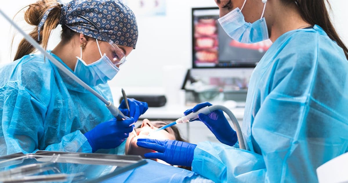 Photo d’un chirurgien-dentiste et d’une assistante réalisant une intervention sur un patient