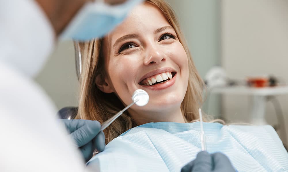 Photo d’une patiente souriante sur un fauteuil dentaire lors d’un examen orthodontique