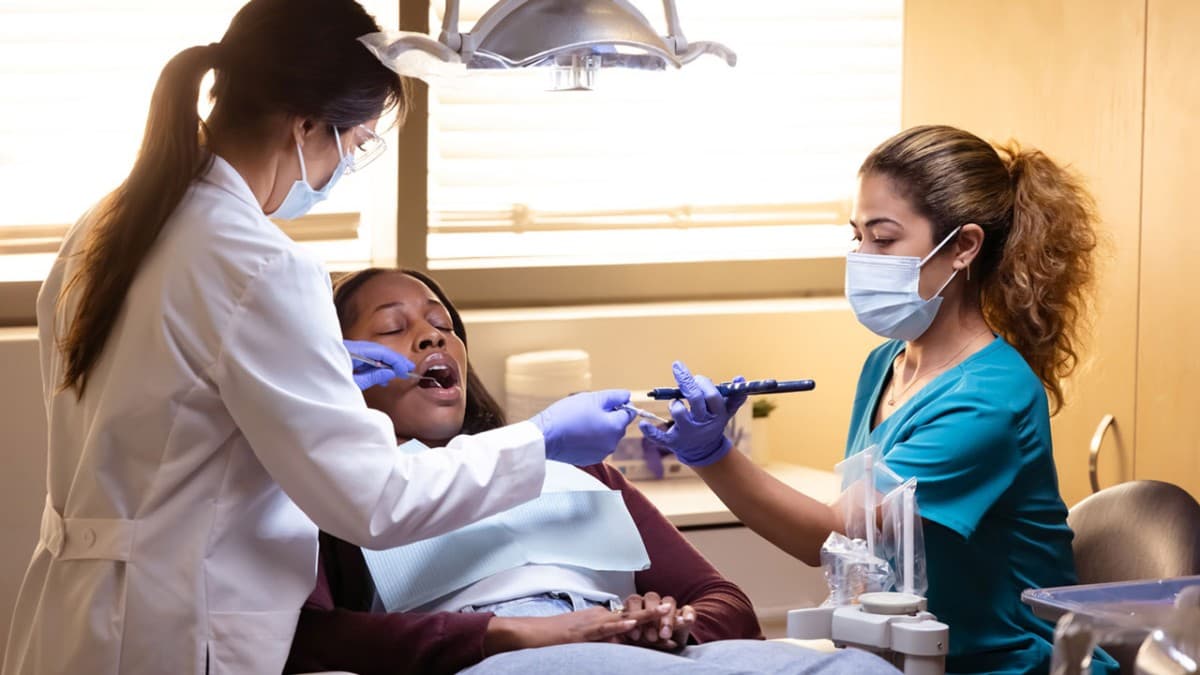 Photo d’une assistante dentaire et d’une dentiste soignant une patiente sur un fauteuil dentaire
