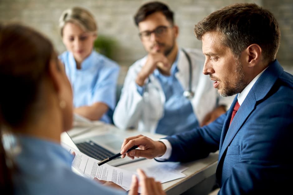 Photo d’un homme en costume présentant des documents lors d’une réunion avec des professionnels de santé