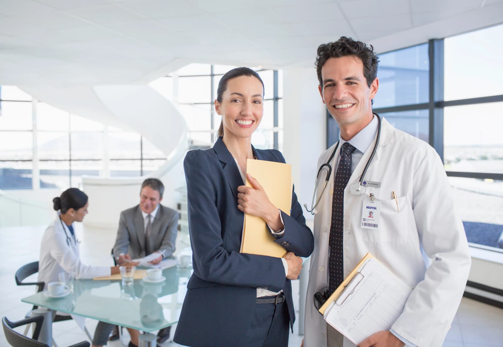 Photo d’une femme en tailleur et d’un médecin souriant dans un hall hospitalier moderne