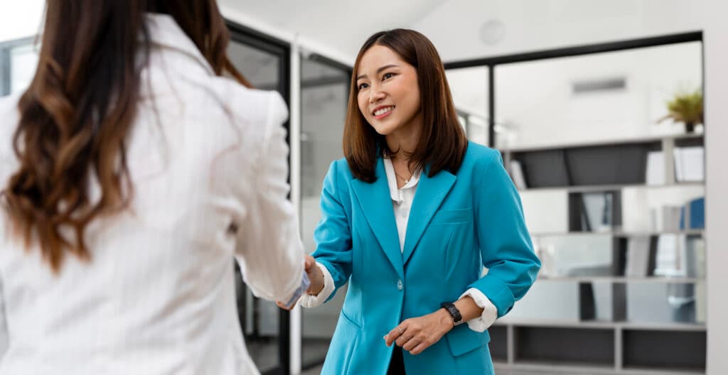 Photo de deux femmes se serrant la main dans un bureau moderne lors d’une rencontre professionnelle