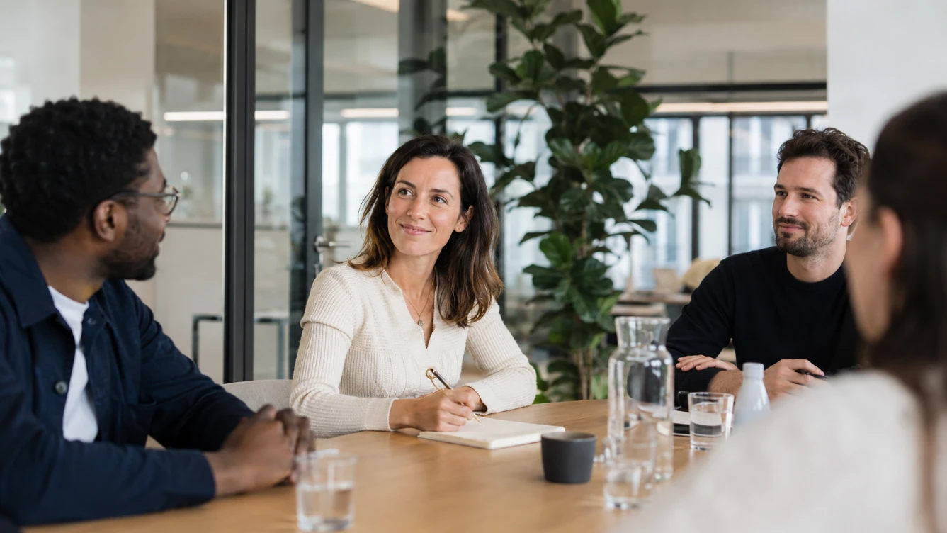 Nouveau collaborateur accueilli par son equipe le premier jour dans une salle de reunion chaleureuse